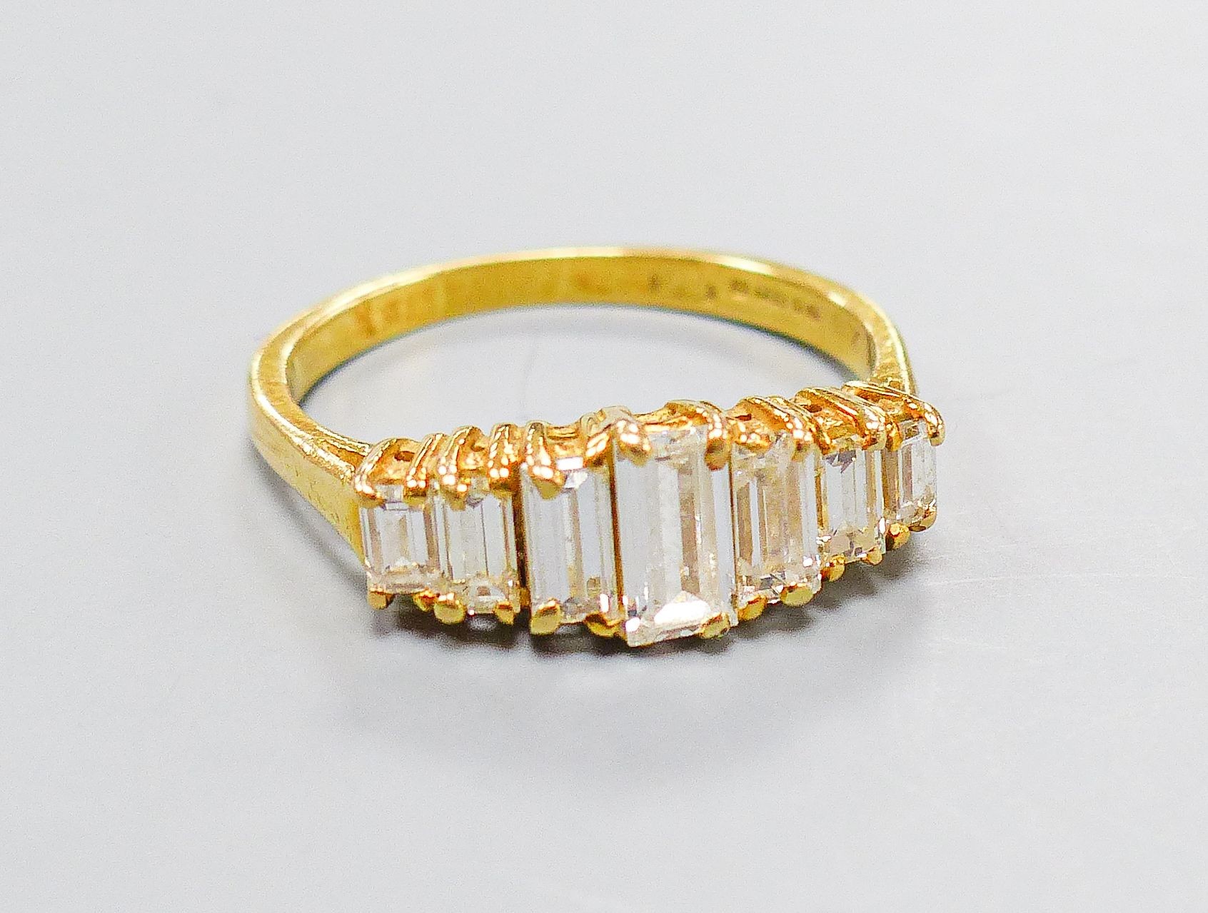 A modern 18ct gold and graduated seven stone baguette cut diamond set half hoop ring, size O, gross weight 4.1 grams.